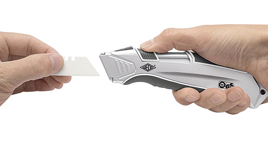 The spring-loaded trapezoidal blade retracts immediately after cutting (no need to hold the slide while cutting). The solid aluminum body with a rubberized grip area fits comfortably and securely in the hand. By placing a blade slider on top of the tool, the cutter can be used by both right- and left-handed users. Easy blade change from integrated magazine with 3 spare blades. TÜV/GS approved. Approx size: 16,5 x 2,0 x 4,0 cm, weight approx: 106 g, color: silver/anthracite/white. Supplied in a blister pack with 1 trapezoidal ceramic blade in an integrated magazine. Optional belt holder with clip and attachment ring for cutter available